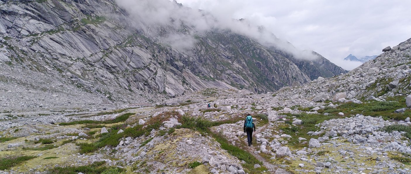 Bergige, steinige Landschaft und eine Person, die darin wandert. 