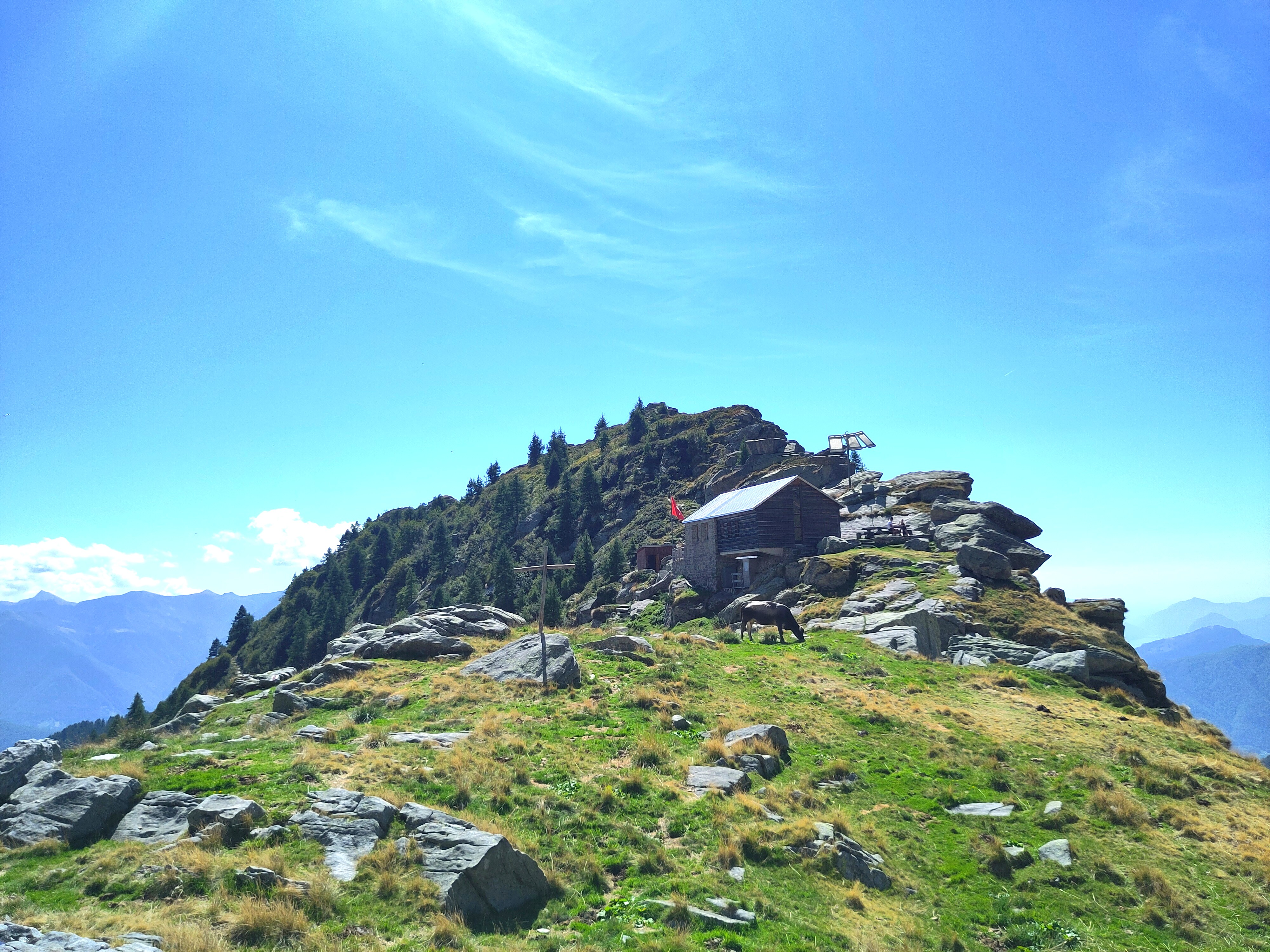 Verschneiter Wegweiser vor weisser Bergkulisse.